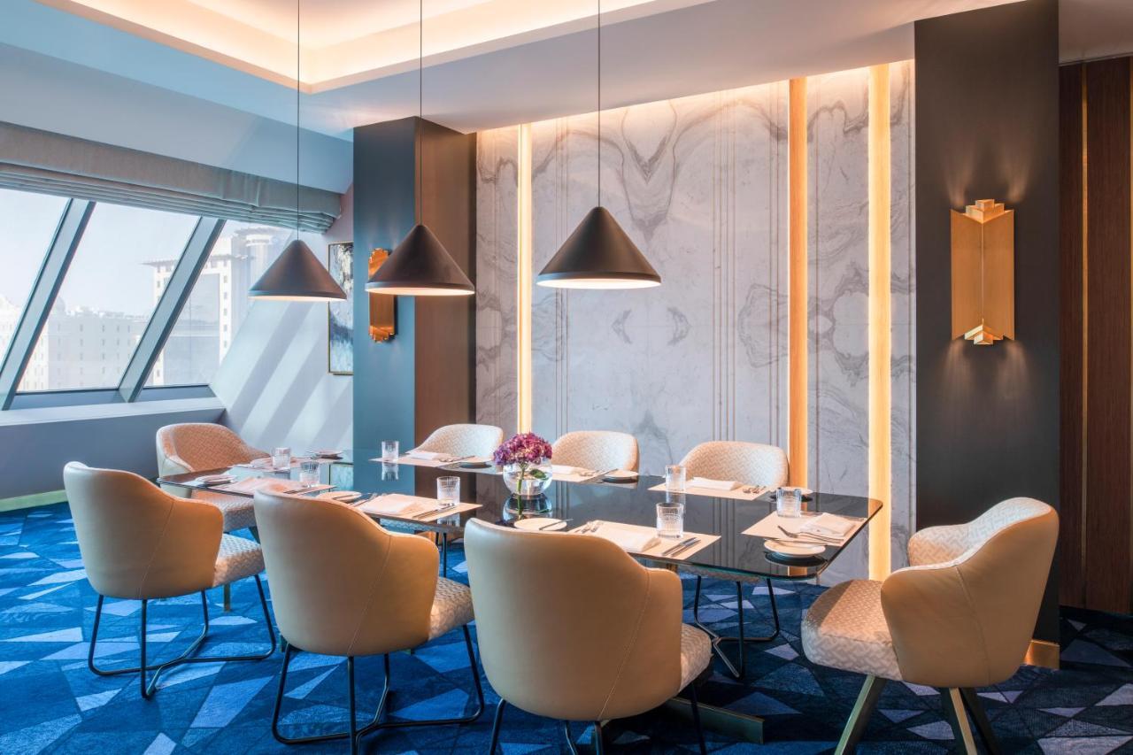 Steigenberger Hotel Ad Dawhah Esterno foto The photo showcases a stylish meeting room. It features a modern, elegant design with a large rectangular table surrounded by plush chairs. The room has a contemporary color palette, primarily using soft beige and rich blue tones. Large windows allow