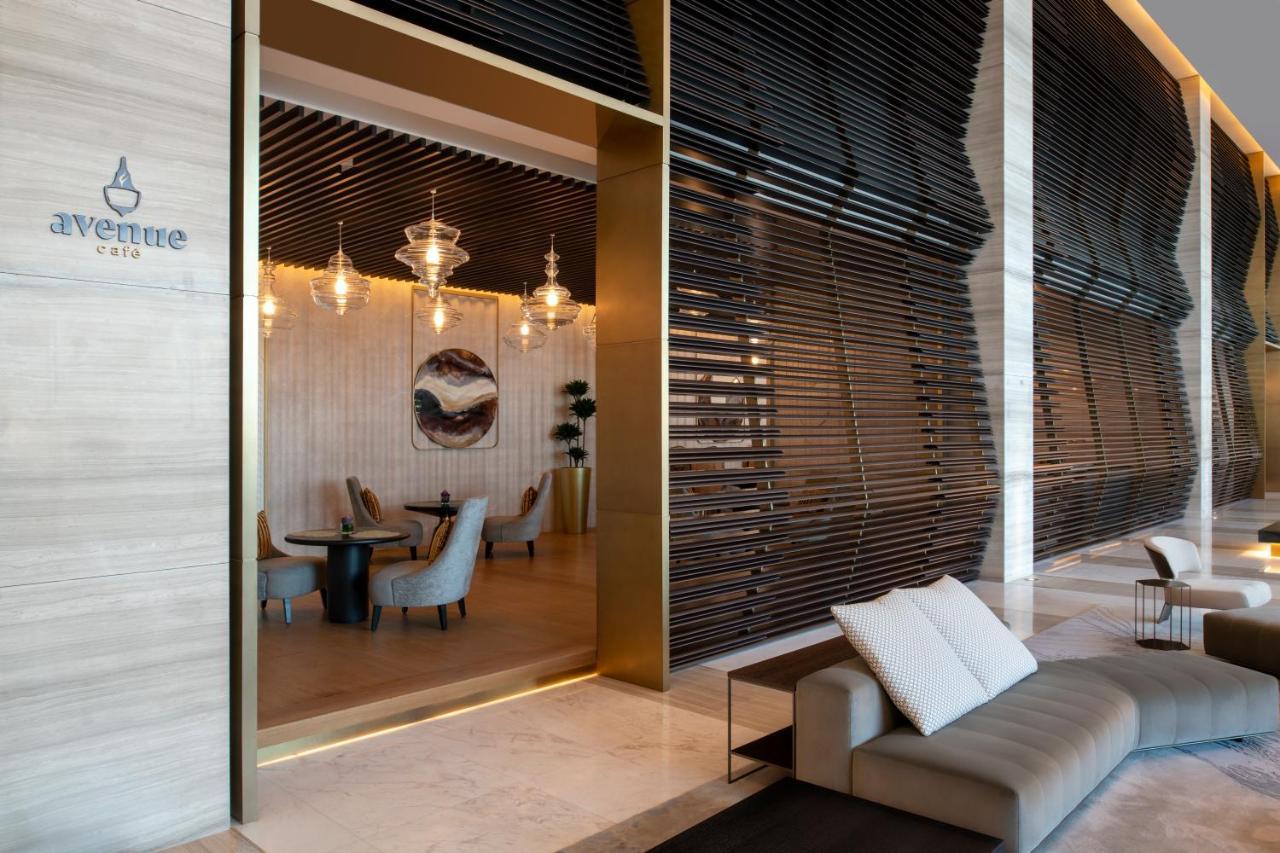 Steigenberger Hotel Ad Dawhah Esterno foto The photo shows a modern and elegant interior space of a café or restaurant. There is a large entrance framed in gold that leads into the café area, which features stylish furniture. Inside, you can see several chairs and tables, along with decorativ