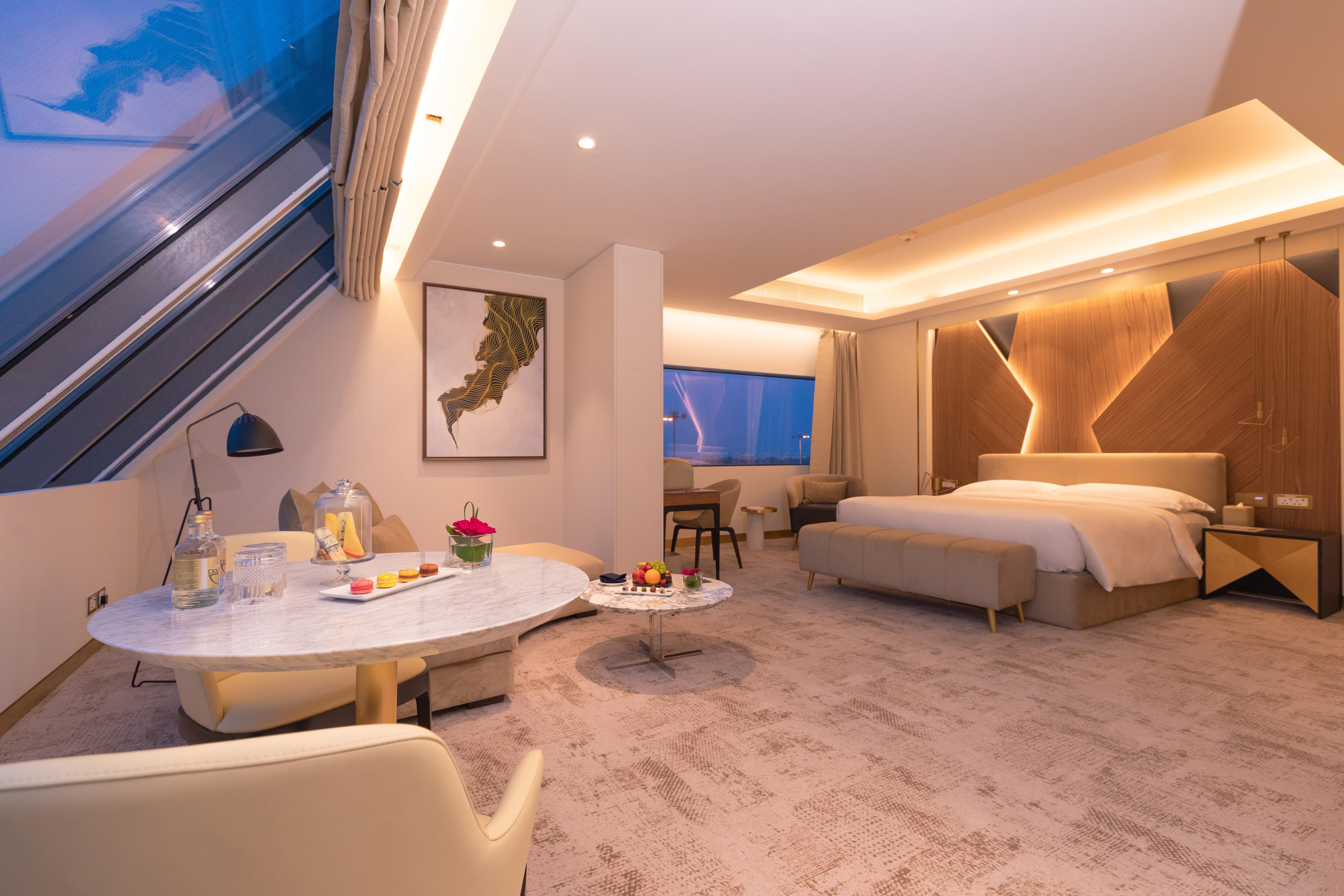 Steigenberger Hotel Ad Dawhah Esterno foto The photo shows a modern hotel room featuring a spacious layout with minimalist decor. The room includes a large bed with elegant bedding, soft lighting, and contemporary furnishings. A seating area with a small table and chairs is present, along wit