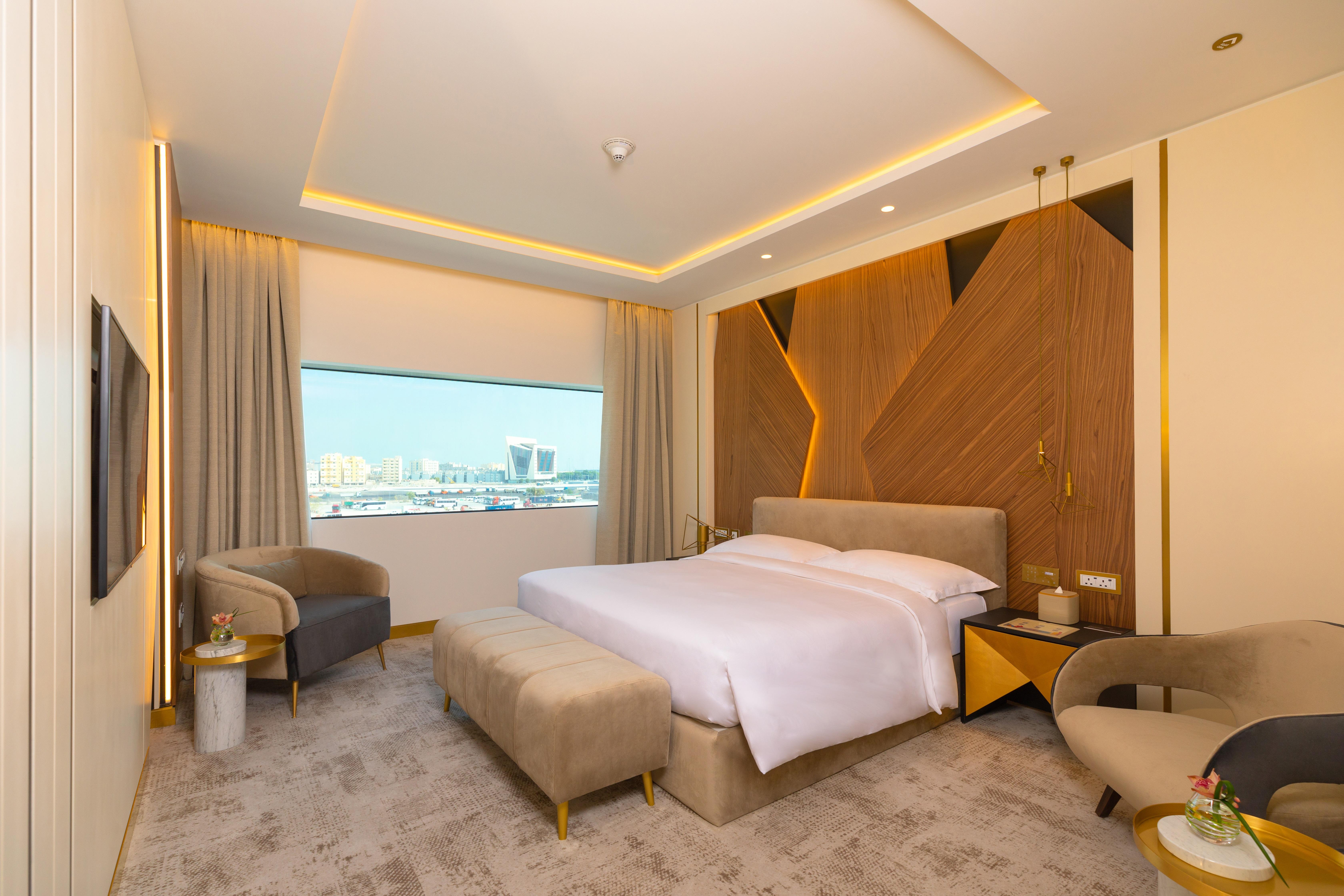 Steigenberger Hotel Ad Dawhah Esterno foto The photo showcases a modern hotel room with a stylish and contemporary design. It features a spacious layout with a large bed placed in the center, dressed in white linens. Behind the bed is an accent wall made of wood, which adds warmth and texture