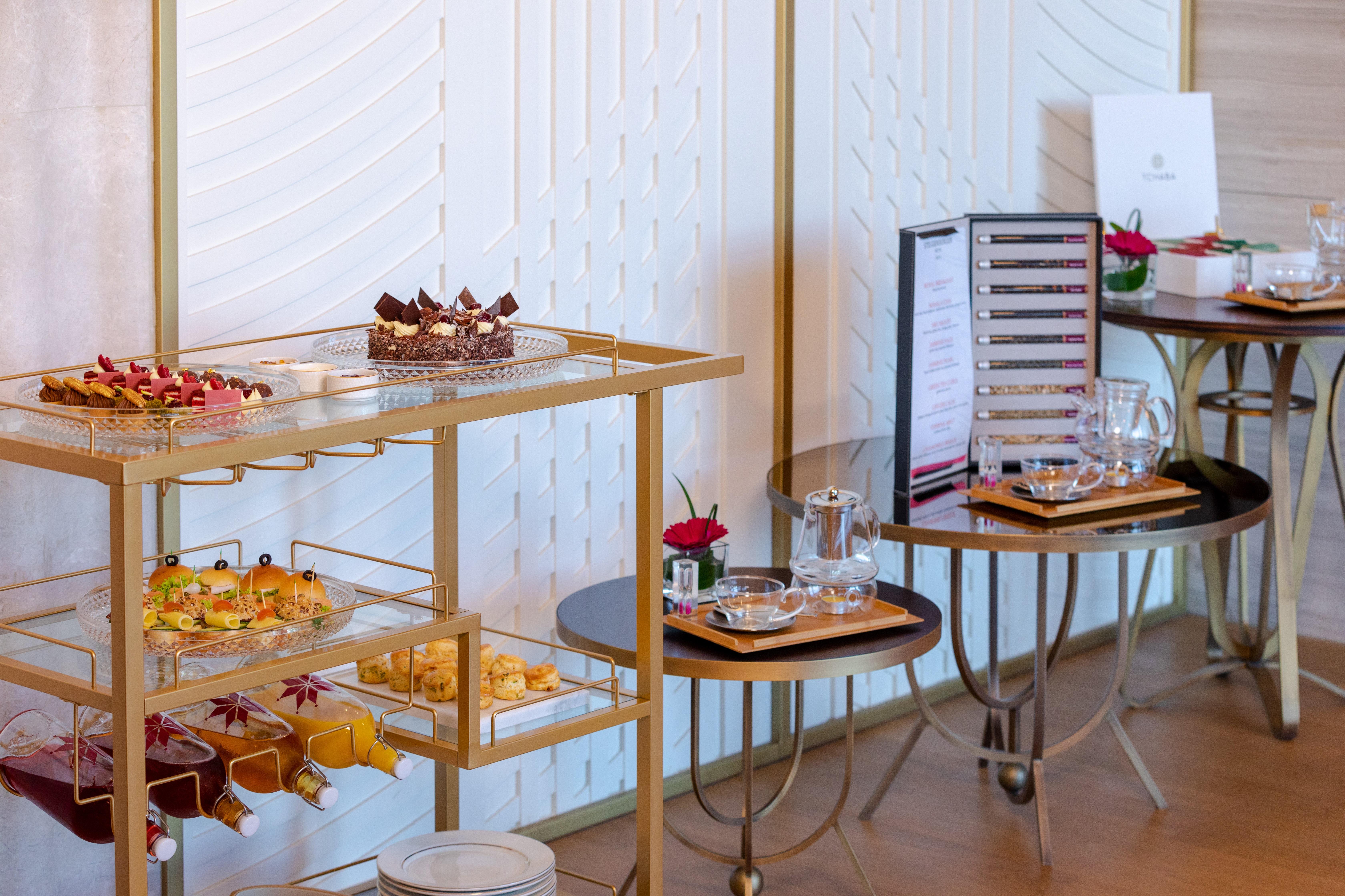 Steigenberger Hotel Ad Dawhah Esterno foto The photo shows a beautifully arranged buffet table featuring a variety of desserts and snacks. There is a gold cart displaying an assortment of pastries and small treats, including colorful hors d'oeuvres and mini desserts, likely for a high-end eve