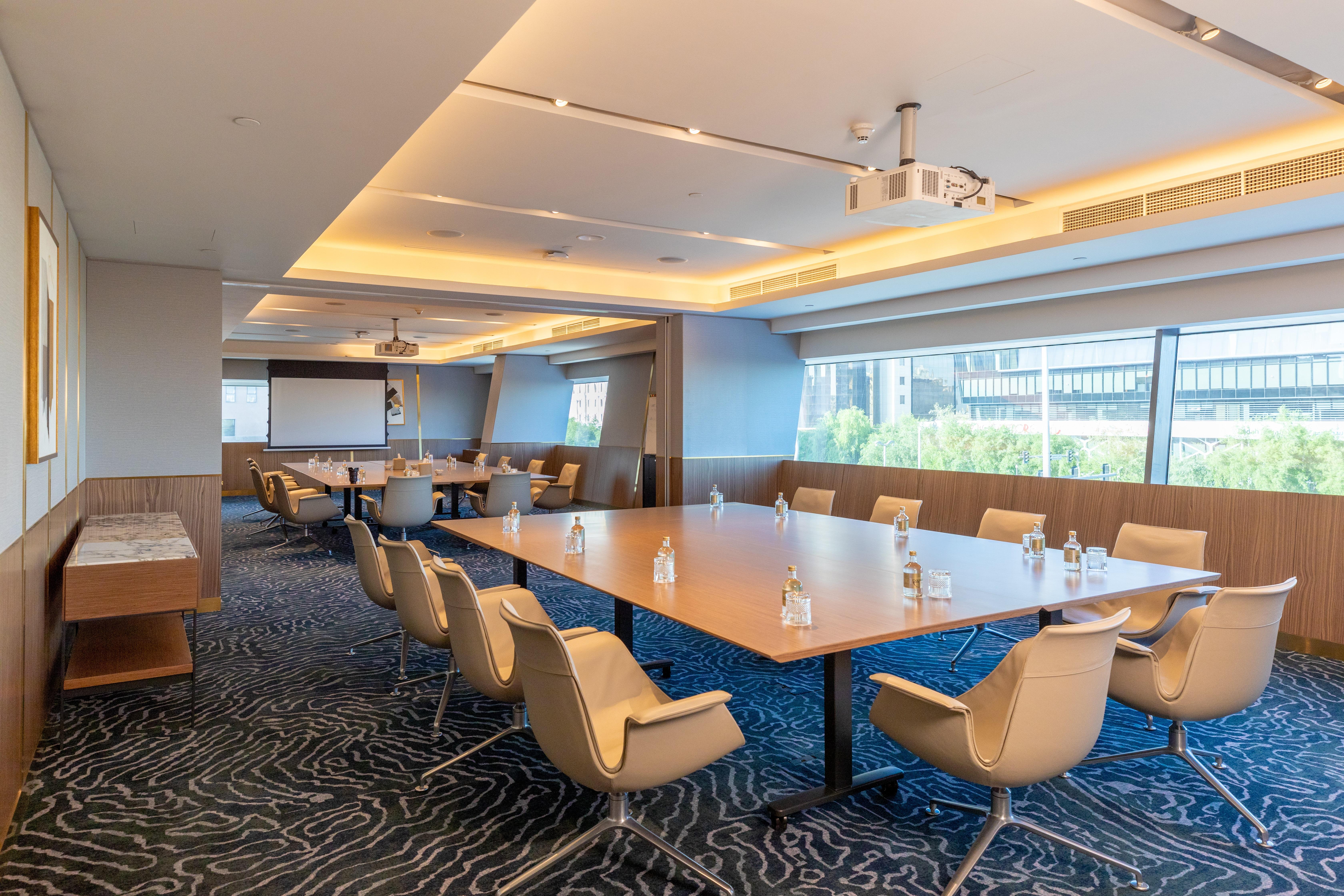 Steigenberger Hotel Ad Dawhah Esterno foto The photo shows a modern conference room. It features large windows that let in natural light, illuminating the space. In the center, there is a large rectangular table surrounded by several ergonomic chairs. The table has glass water bottles on it, 
