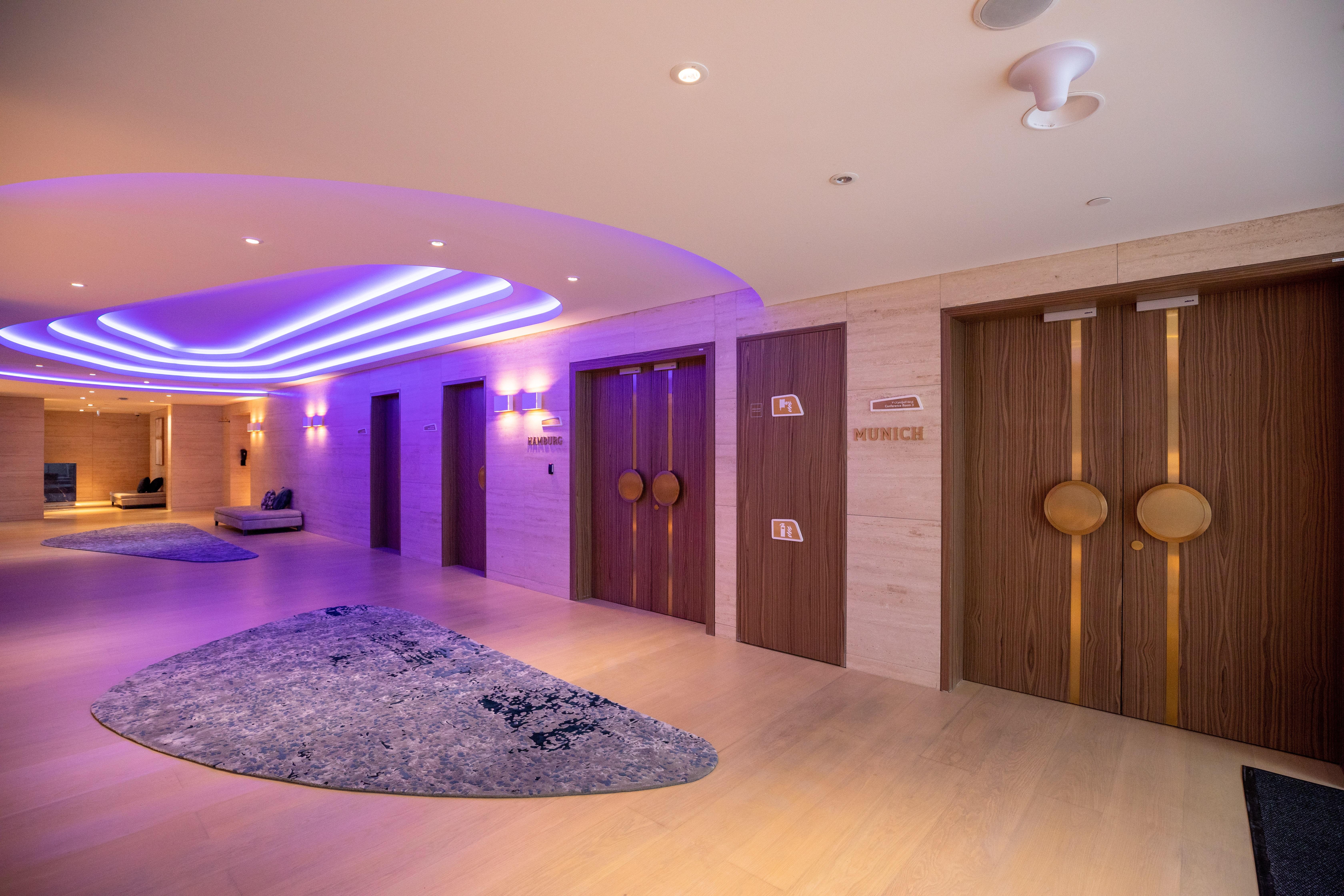 Steigenberger Hotel Ad Dawhah Esterno foto The photo shows a modern interior space, likely a hotel or spa. There are two prominent wooden doors with circular handles, which could be entrances to different facilities. The walls are adorned with subtle lighting, creating a warm and inviting amb